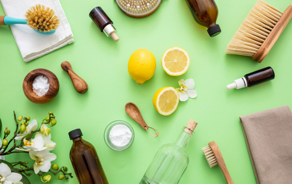 Eco cleaning household background. Cleaning products homemade safe non toxic flat lay, baking soda, lemon vinegar and fresh spring blossoms on green color background,