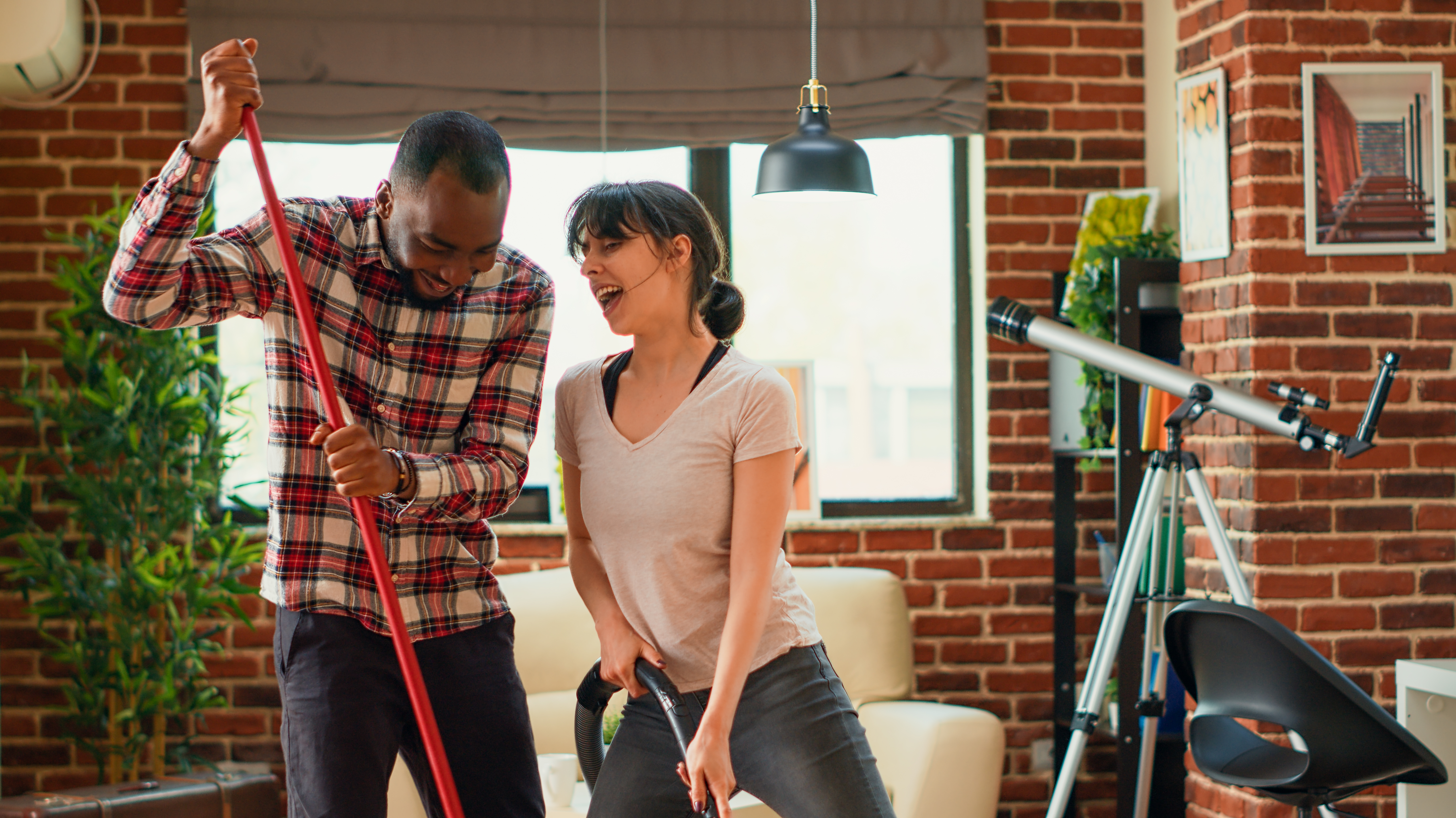 A couple laughs and cleans together in a bright kitchen, showcasing the fun side of household chores. Perfect inspiration for partners everywhere." st pete cleaning service, cleaning service st pete, cleaning, joy of cleaning, happy couple image